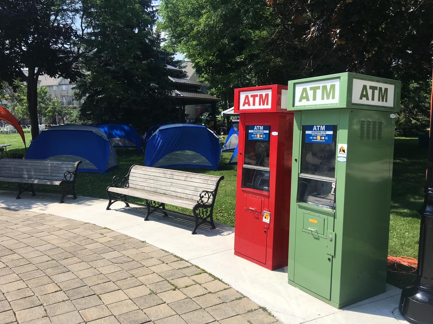 Red and green ATM Systems machines placed along a park pathway