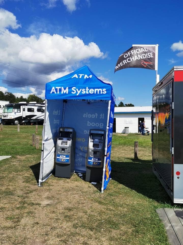 ATM Systems branded event tent with two ATMs on a grass field